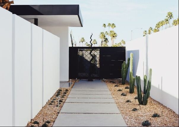 modern landscaping with white rock and pops of greenery alongside a white fence